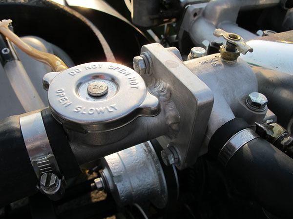 The cooling system pressure cap is closely coupled to the thermostat housing.