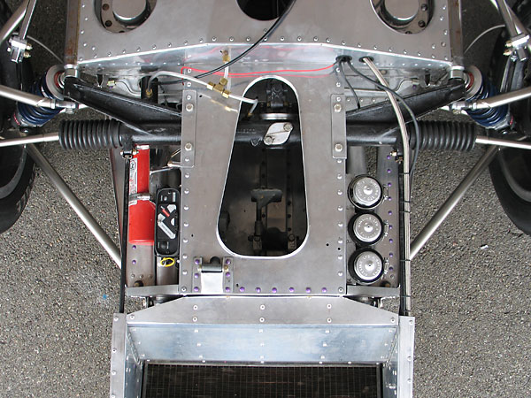 Two thin radius rods extend forward from bosses on the steering rack to support the cooling system.